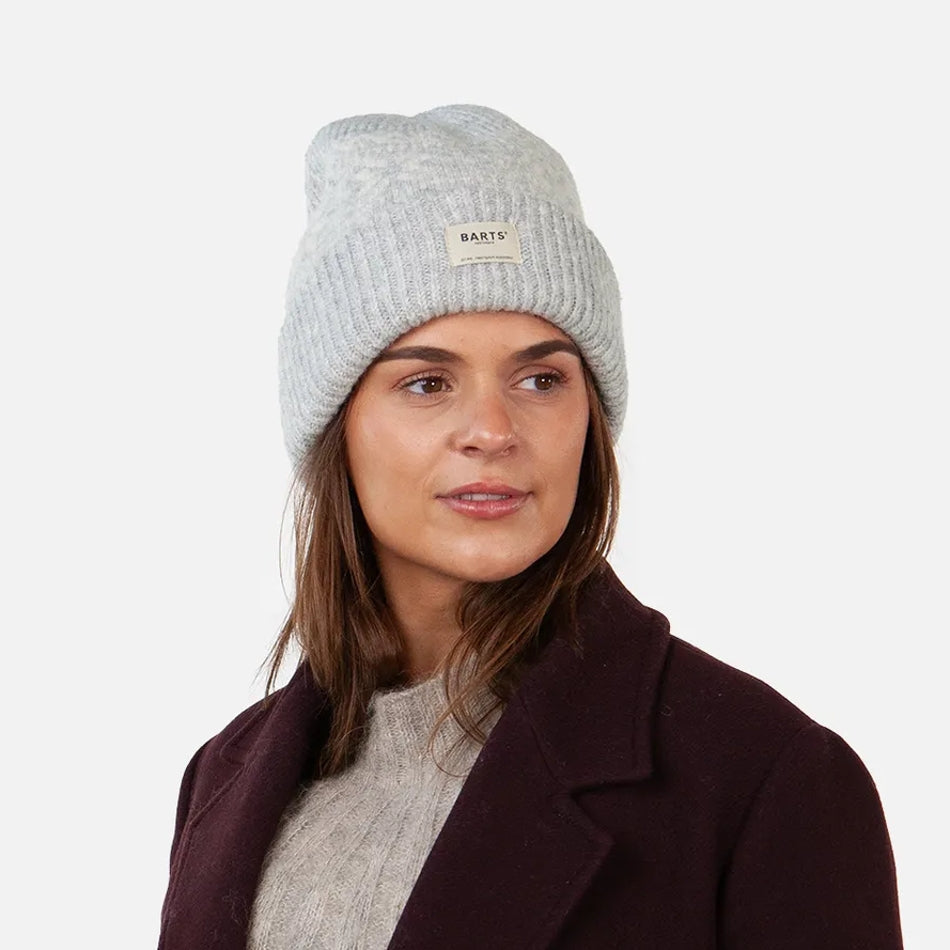 Woman wearing a Barts grey knitted Negomba beanie with a brand logo on a white background