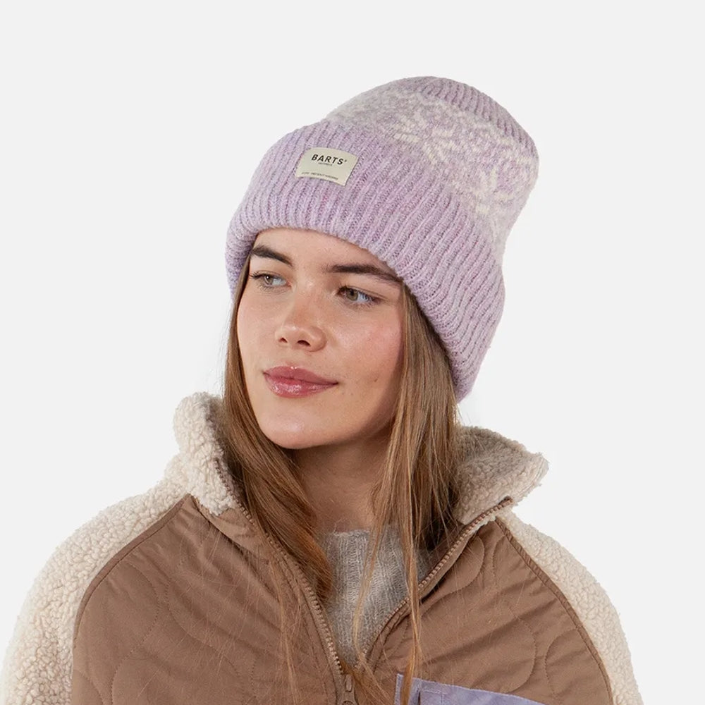 Woman wearing a purple-pink Barts knitted Negomba beanie with a Fair Isle pattern on a white background
