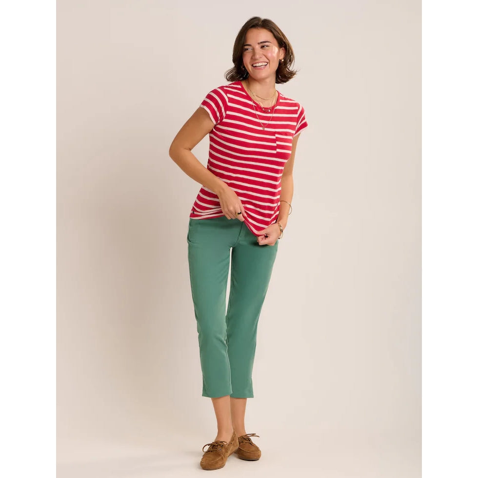 A woman wearing a Brakeburn red and white stripe Coastline short sleeve t-shirt with a pocket on the chest with turquoise capri trousers and brown shoes.