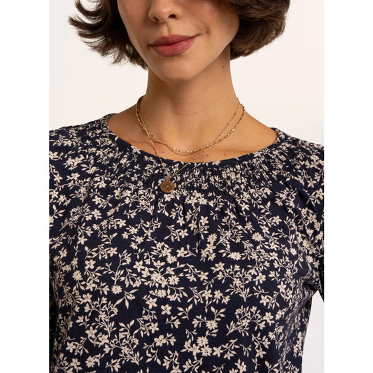 Close-up view of the neckline of a woman wearing a Brakeburn Brielle 3/4 sleeve t-shirt in navy with a white floral pattern and elasticated neckline trim.