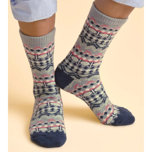 Model wearing a pair of Brakeburn womens Plush Socks with a grey, navy and pink Nordic pattern on a beige background.