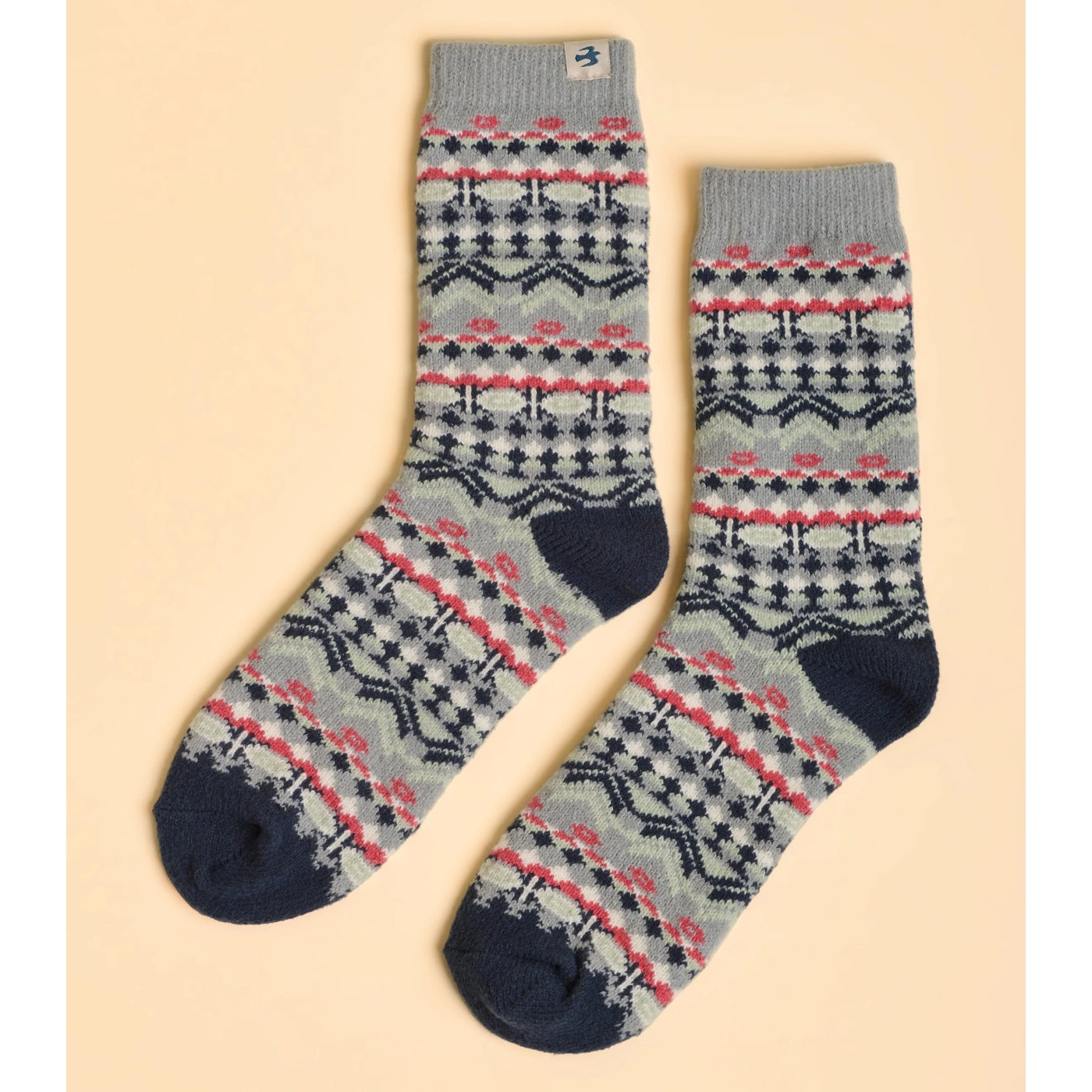 A pair of womens Brakeburn Nordic pattern socks in grey and navy, with a bird logo on a beige background.