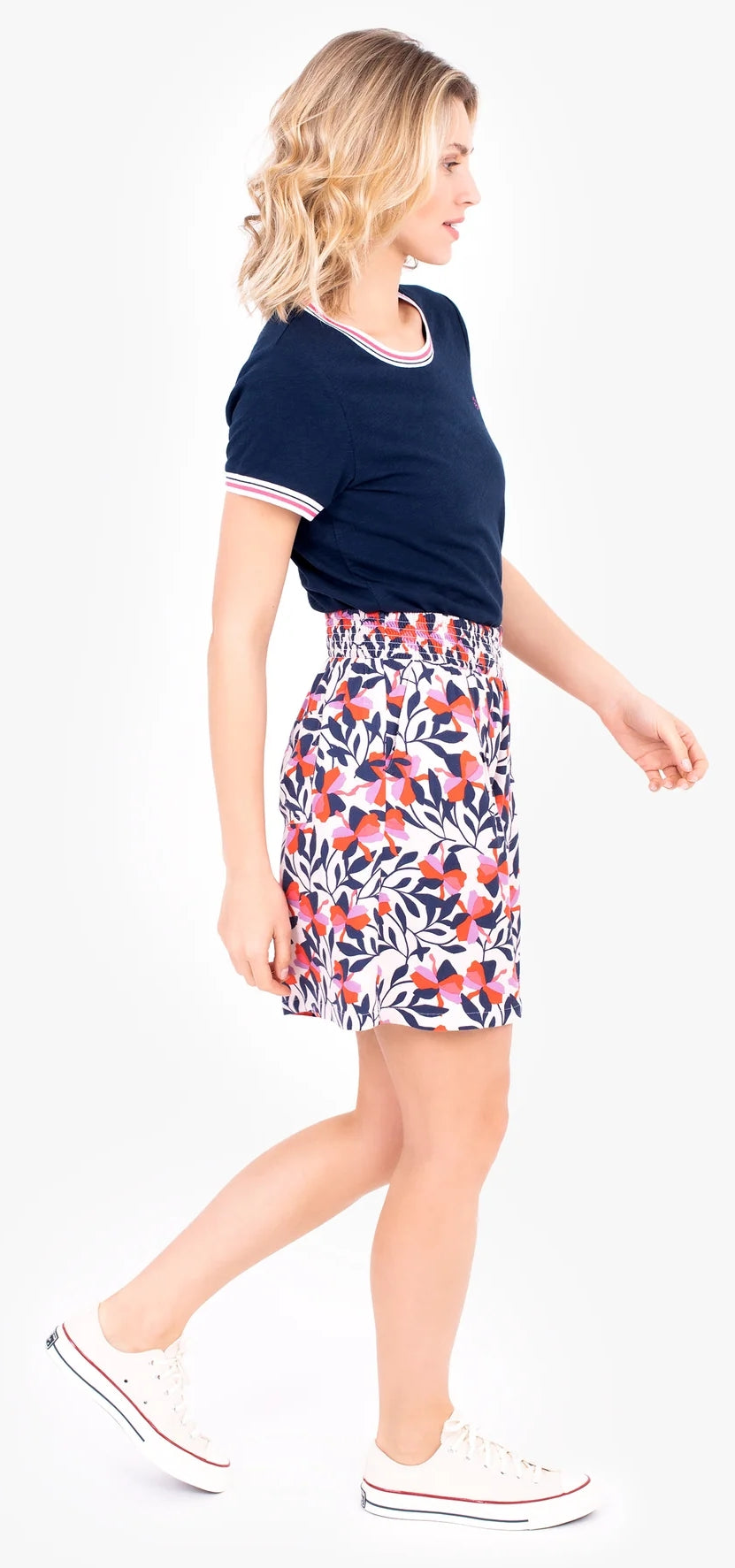 Woman wearing a floral pink pair of Brakeburn Gardinia shorts with a navy t-shirt on a white background