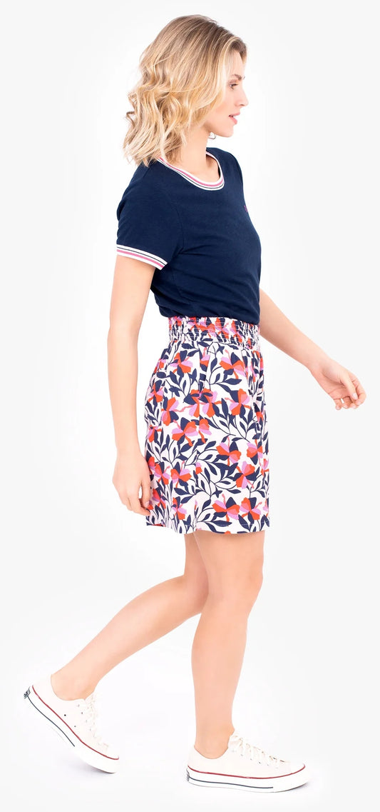Woman wearing a floral pink pair of Brakeburn Gardinia shorts with a navy t-shirt on a white background