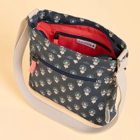 Brakeburn Henna floral-patterned navy cross body bag with a visible brand label on a beige background