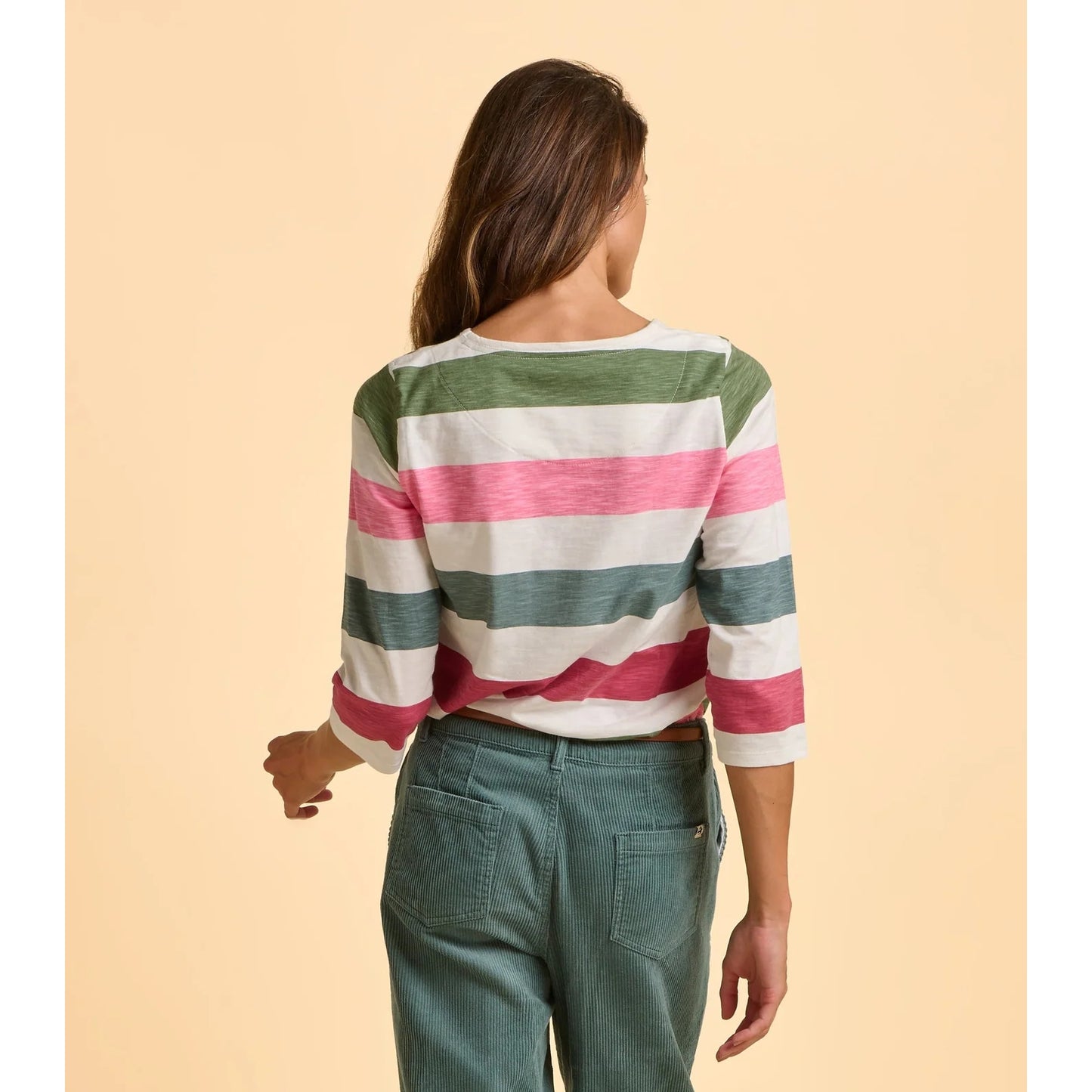 Woman wearing a striped t-shirt and green pants on a beige background