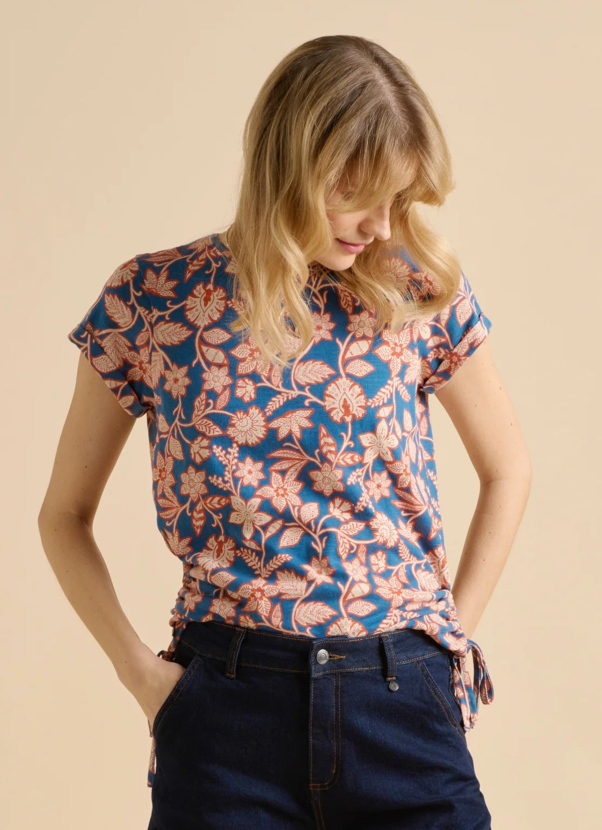 Woman wearing a Brakeburn short sleeve floral pattern Midnight Garden tee in navy with a red and cream floral pattern, on a cream background