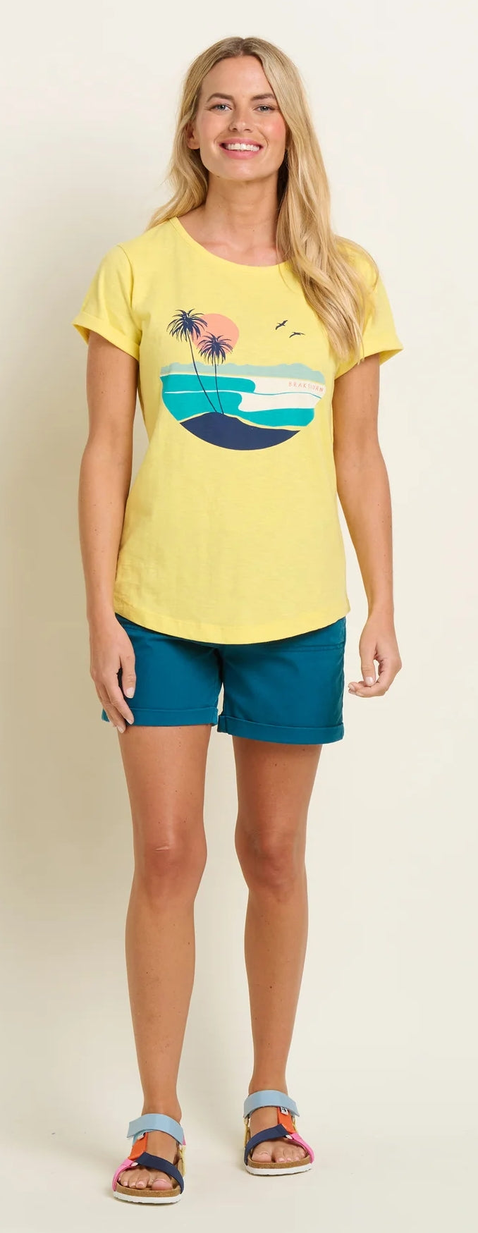 Brakeburn womens yellow t-shirt with tropical beach graphic worn with teal shorts and sandals