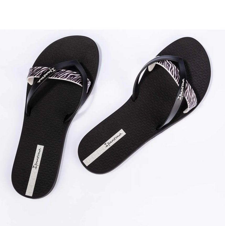 Top view of a pair of women's Ipanema Kirei flip flops, a three strap toepost design in black with a contrasting zebra print strap.