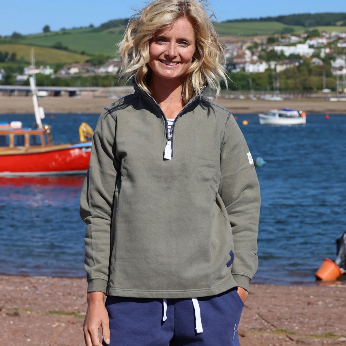 Lazy Jacks womens sweatshirt khaki worn by woman standing near water with boats in background