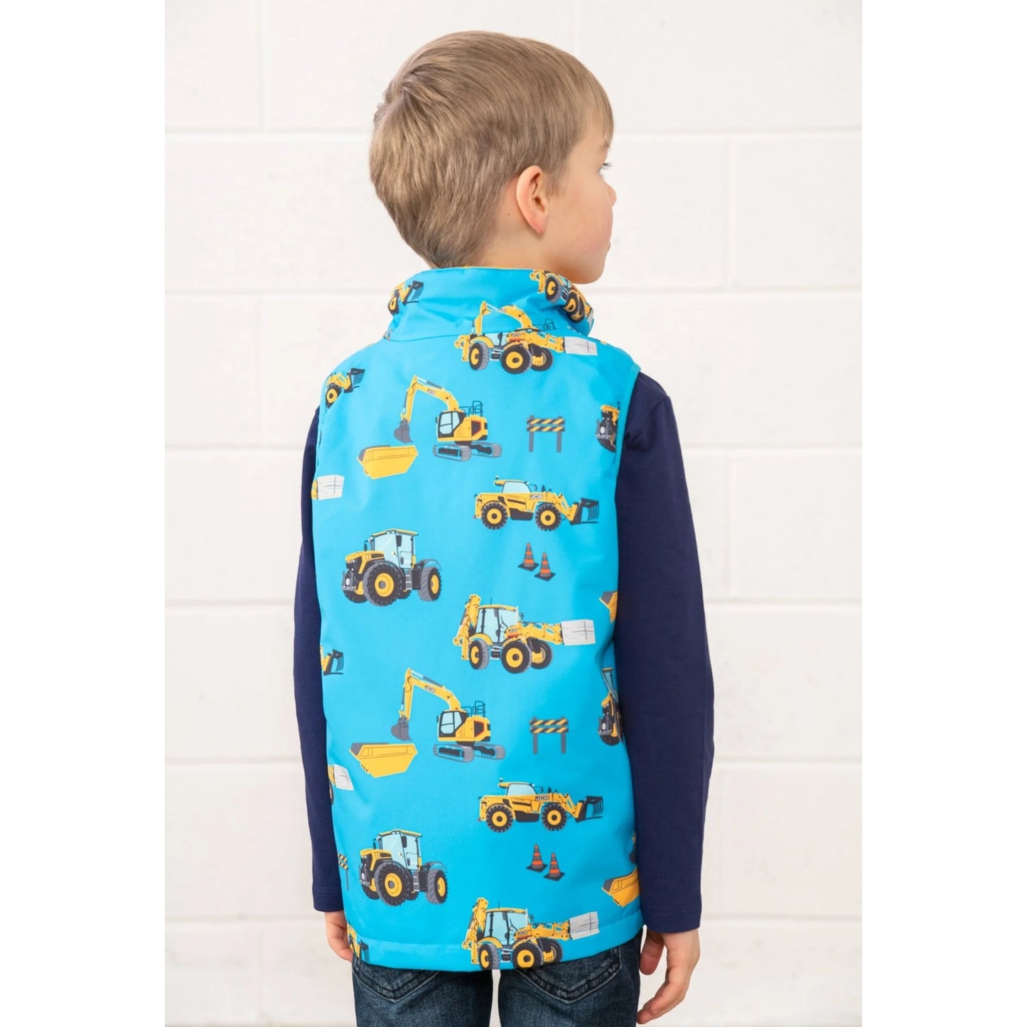 Lighthouse kids blue gilet JCB print worn by child showing back with construction vehicle designs