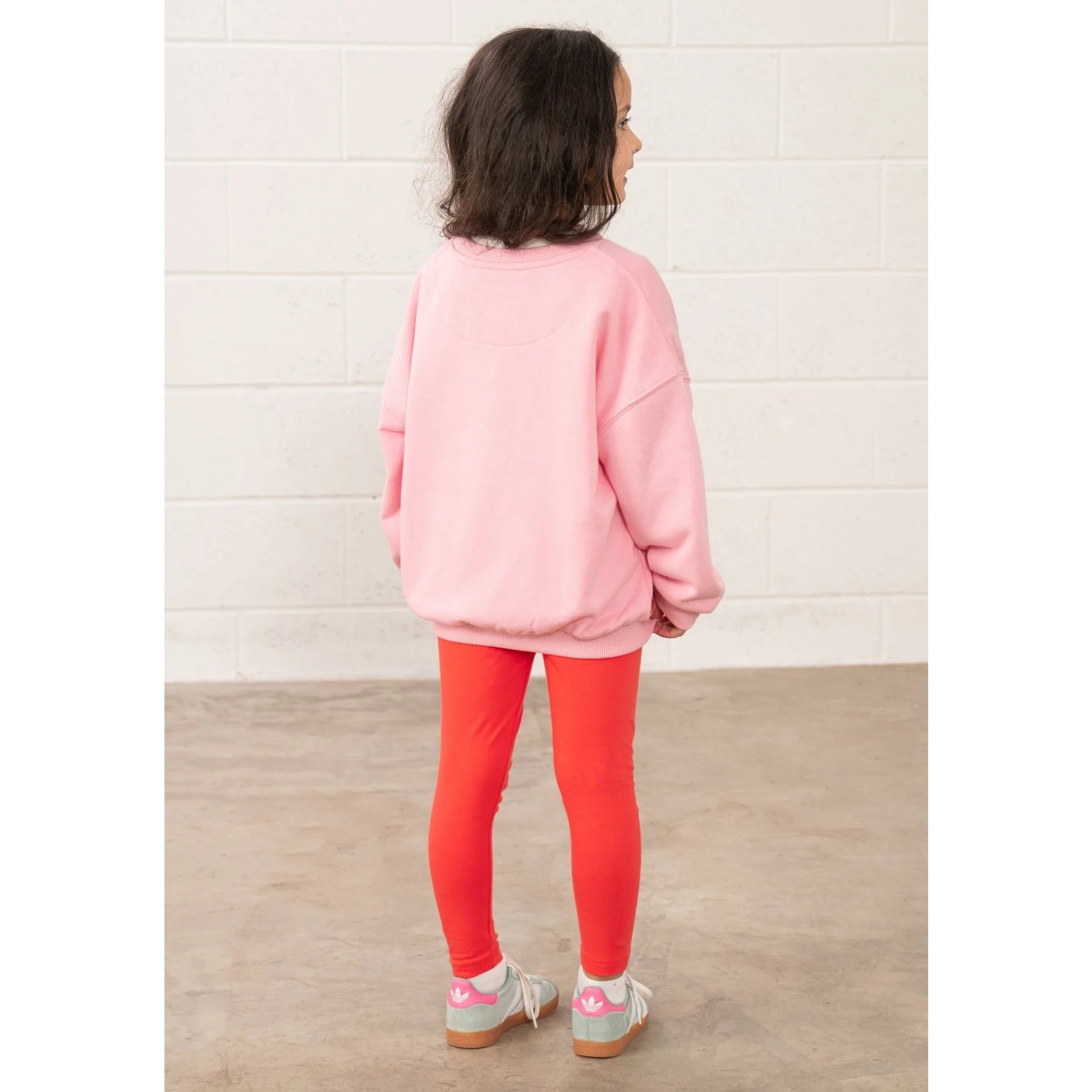 Child wearing a Lighthouse kids Flora sweatshirt Dusky Pink flowers standing facing away on a concrete floor