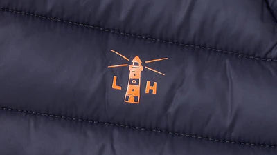 Close-up of Lighthouse kids navy padded coat showing orange lighthouse logo embroidery