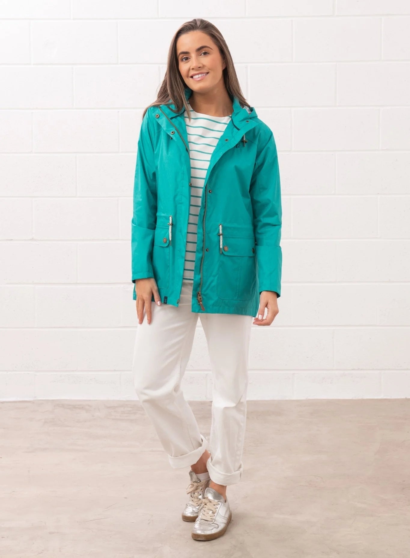 Woman wearing Lighthouse teal womens waterproof jacket with hood and front pockets