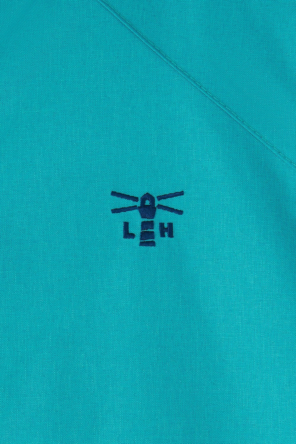Close-up of Lighthouse teal womens waterproof jacket fabric with stitched lighthouse logo