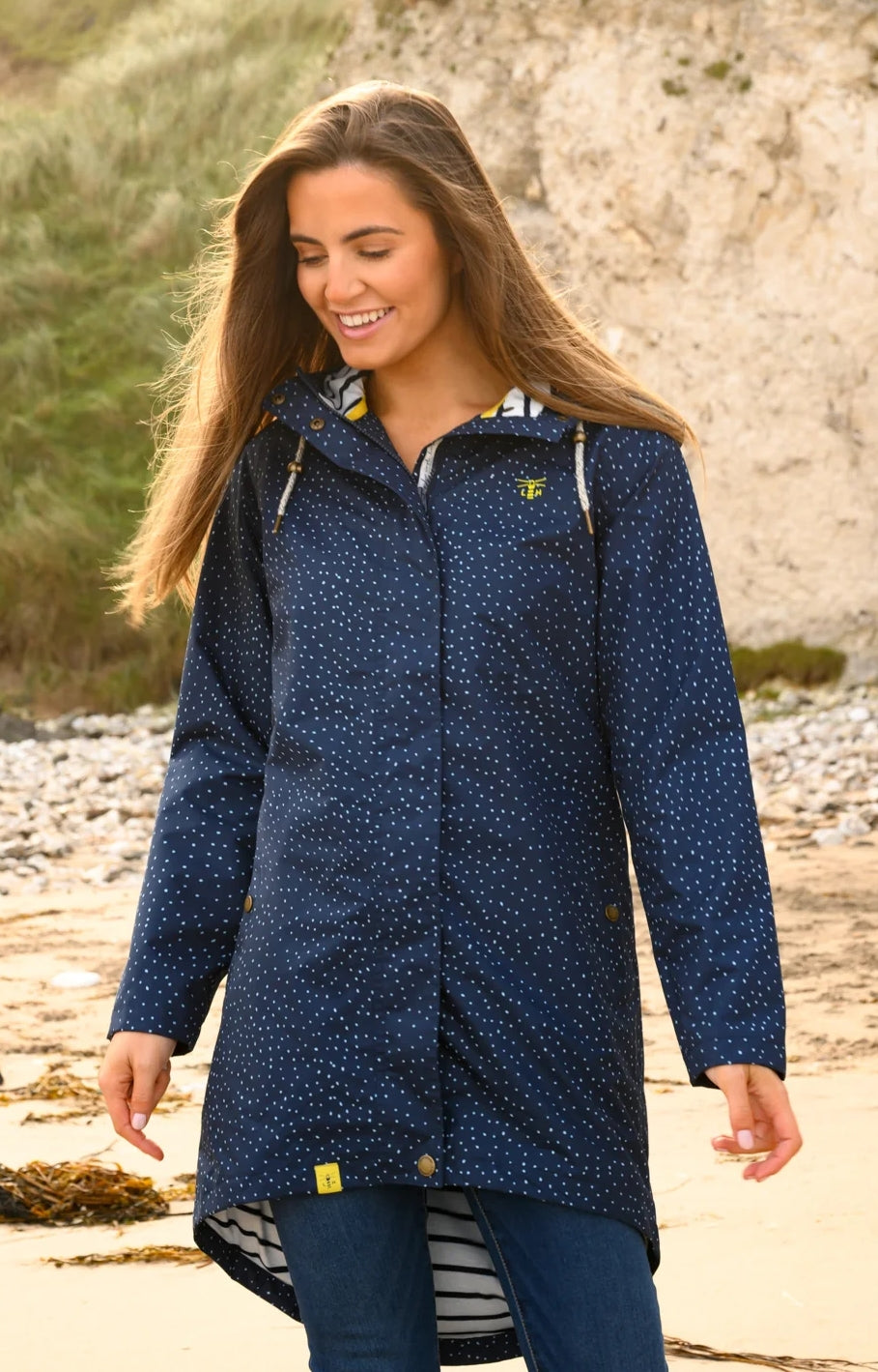 Lighthouse womens beachcomber jacket navy dot worn by smiling woman on beach with hood and dotted pattern