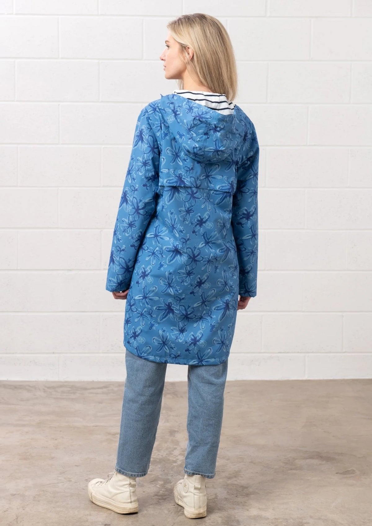 Back view of a woman wearing Lighthouse Womens blue floral jacket with hood and long sleeves