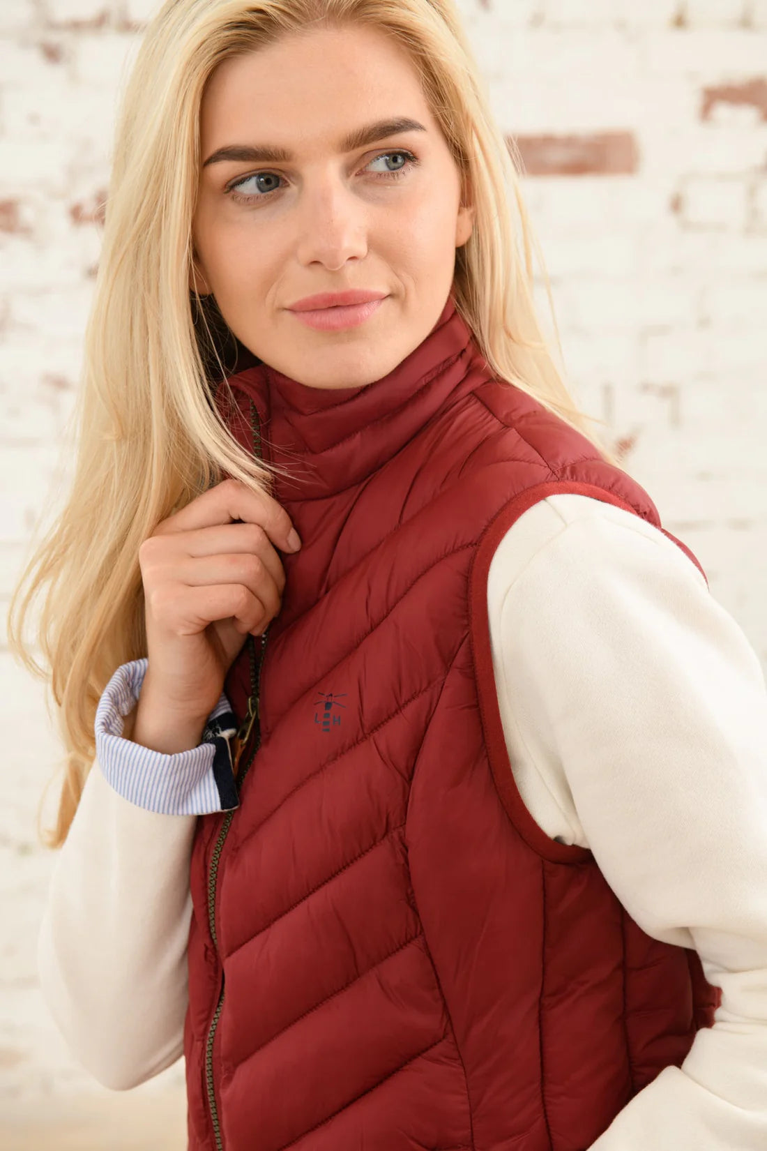 Lighthouse womens Laurel padded gilet red worn by a blonde woman with a white long sleeve shirt