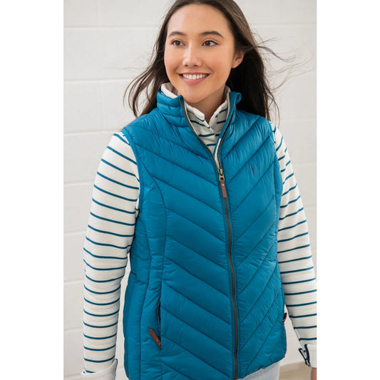Woman wearing a teal blue Lighthouse Laurel puffer gilet over a striped shirt against a white background