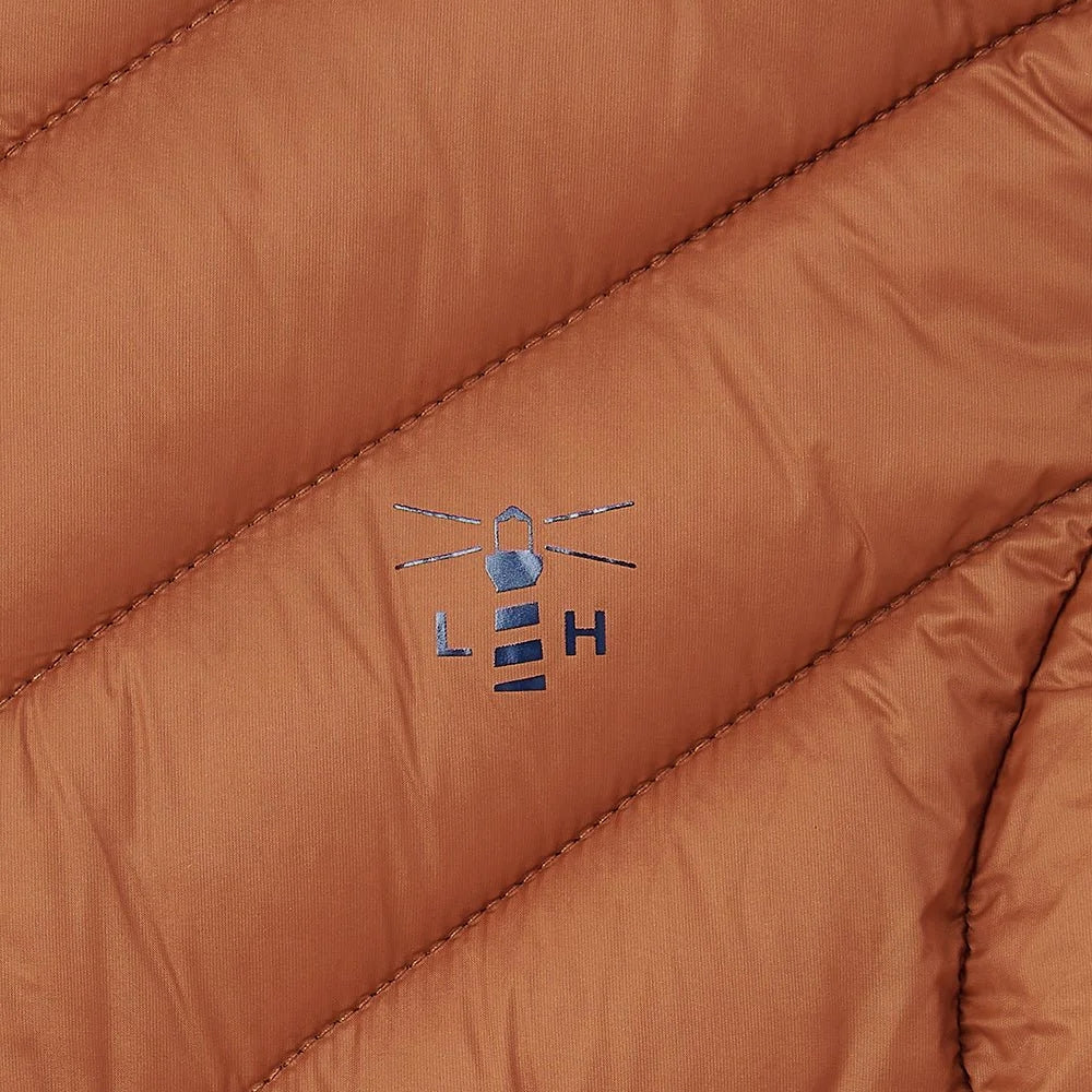 Close-up of rust orange puffer gilet fabric with a Lighthouse clothing logo.