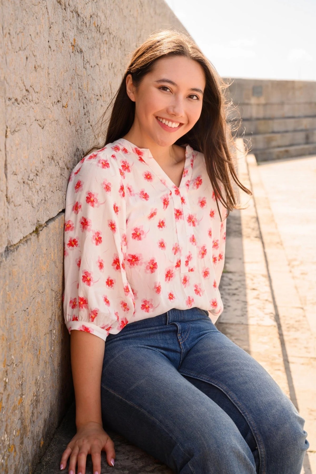 Lighthouse womens Lola blouse white with red floral print worn by smiling woman sitting outdoors
