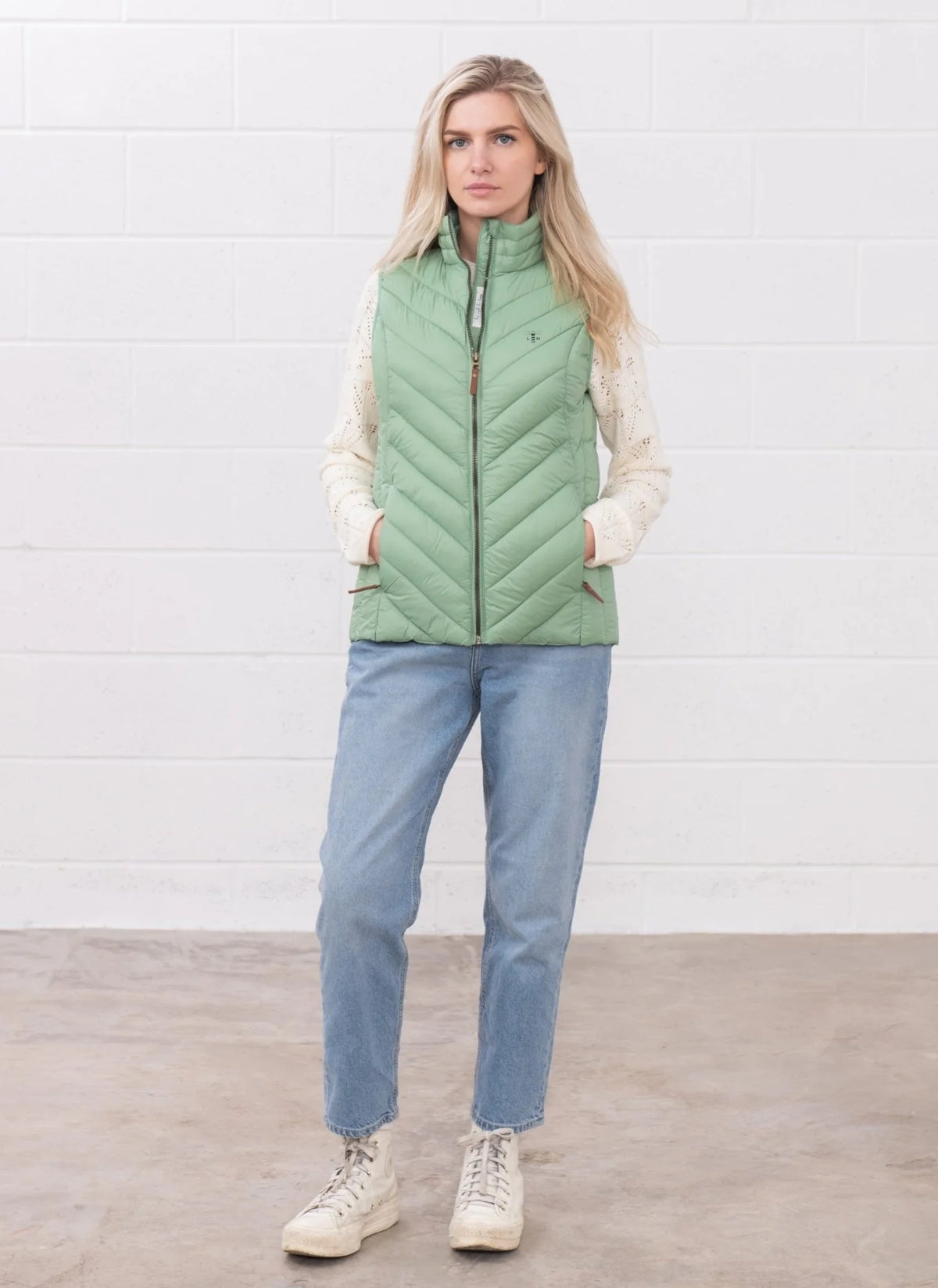 Lighthouse womens padded gilet green worn by woman with hands in pockets standing against white wall