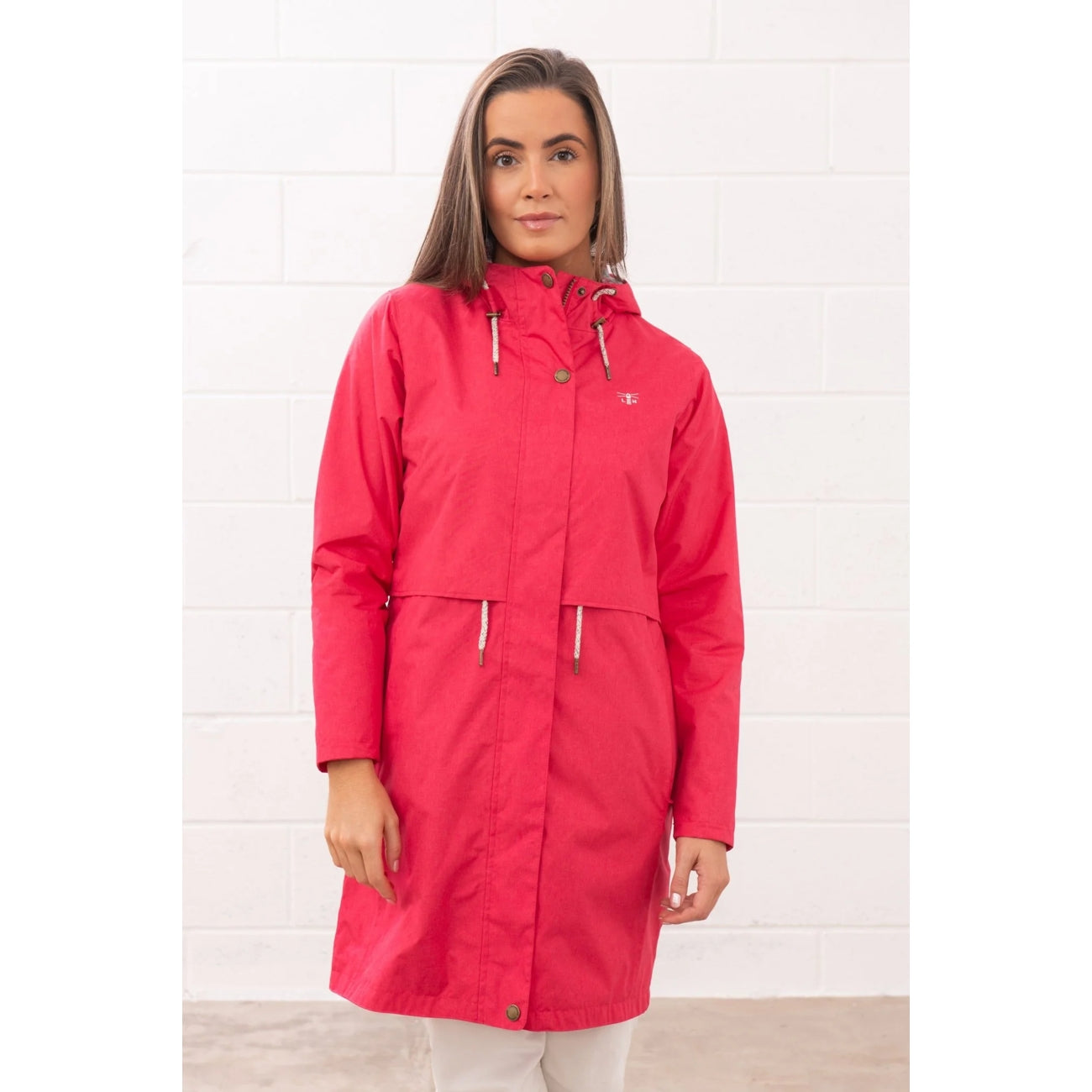 Woman wearing a Lighthouse Pippa 3/4 length waterproof raincoat in Raspberry pink/red zipped up.
