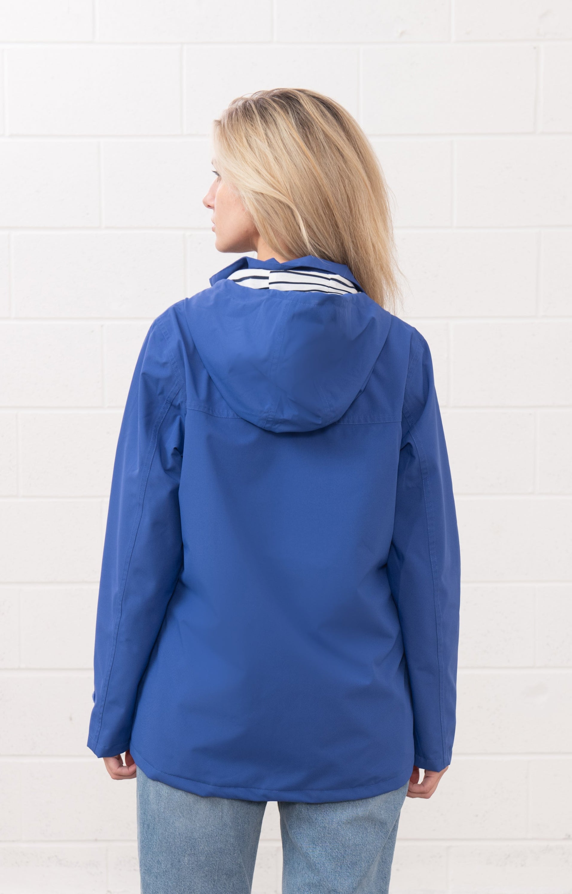 Back view of Lighthouse womens waterproof jacket in blue with hood and long sleeves