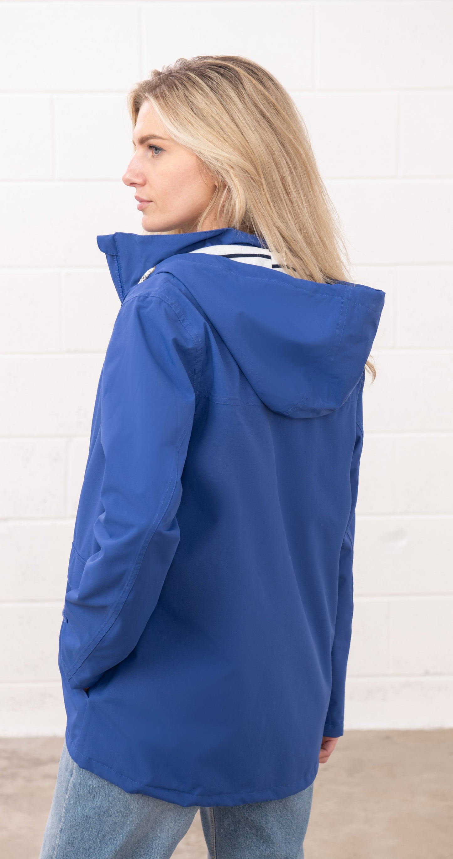 Lighthouse womens waterproof jacket in blue with hood shown from the back on a blonde model