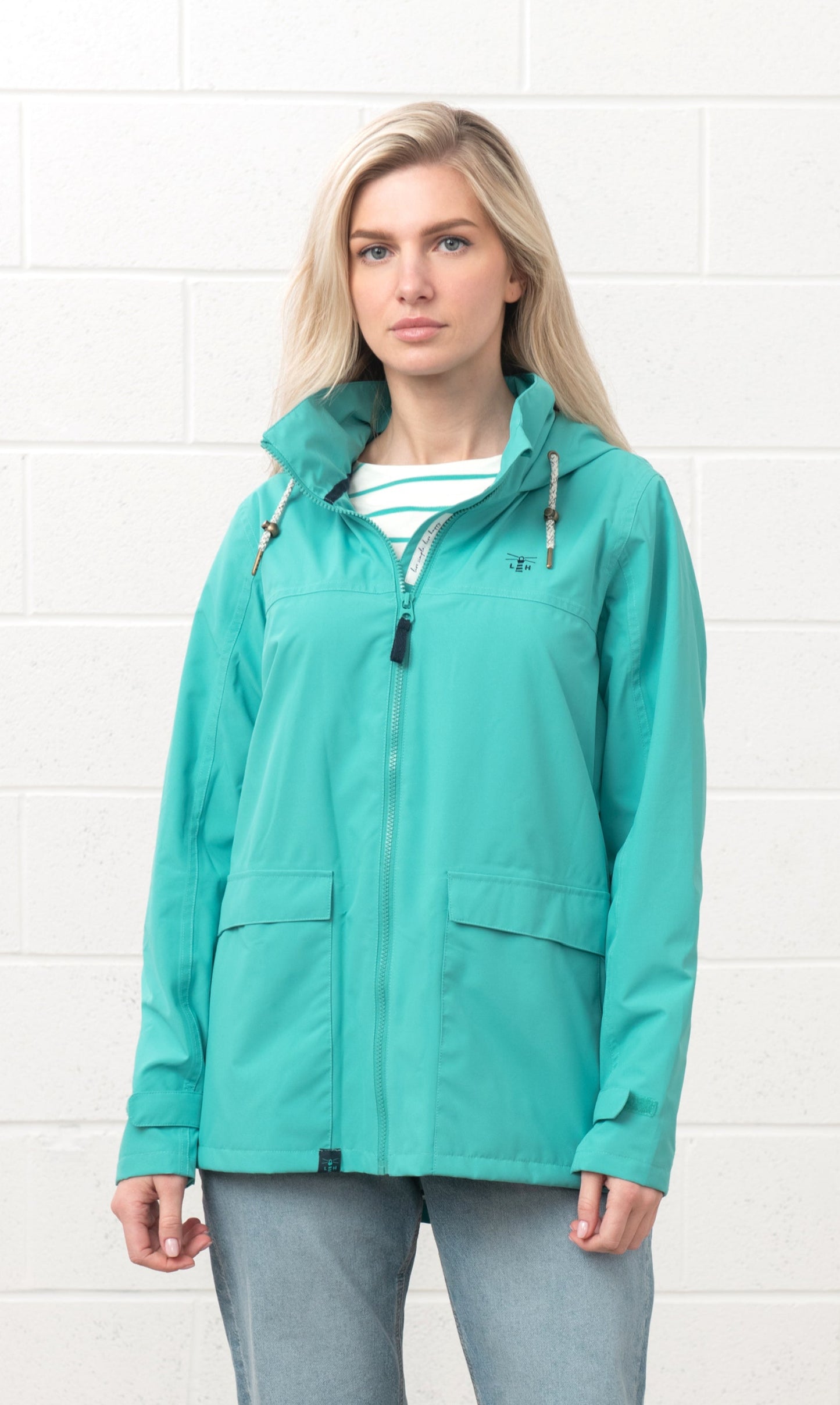 Lighthouse womens waterproof jacket teal worn by a woman with front zipper and adjustable hood