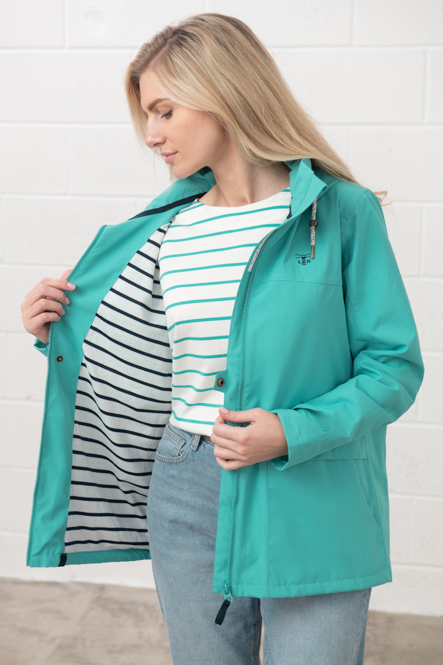 Lighthouse womens waterproof jacket teal shown open with striped lining on model wearing striped shirt and jeans