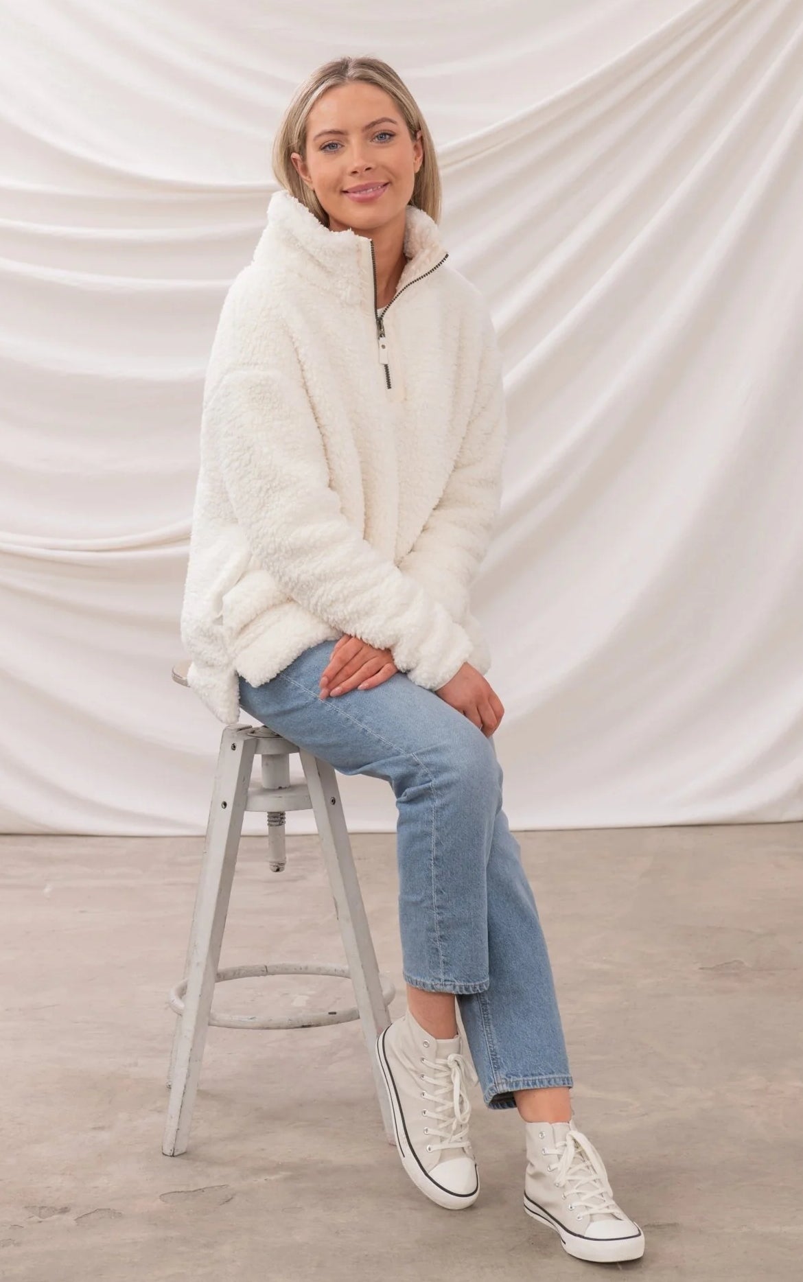 Lighthouse womens zip fleece in white worn by model sitting on stool with casual jeans and sneakers