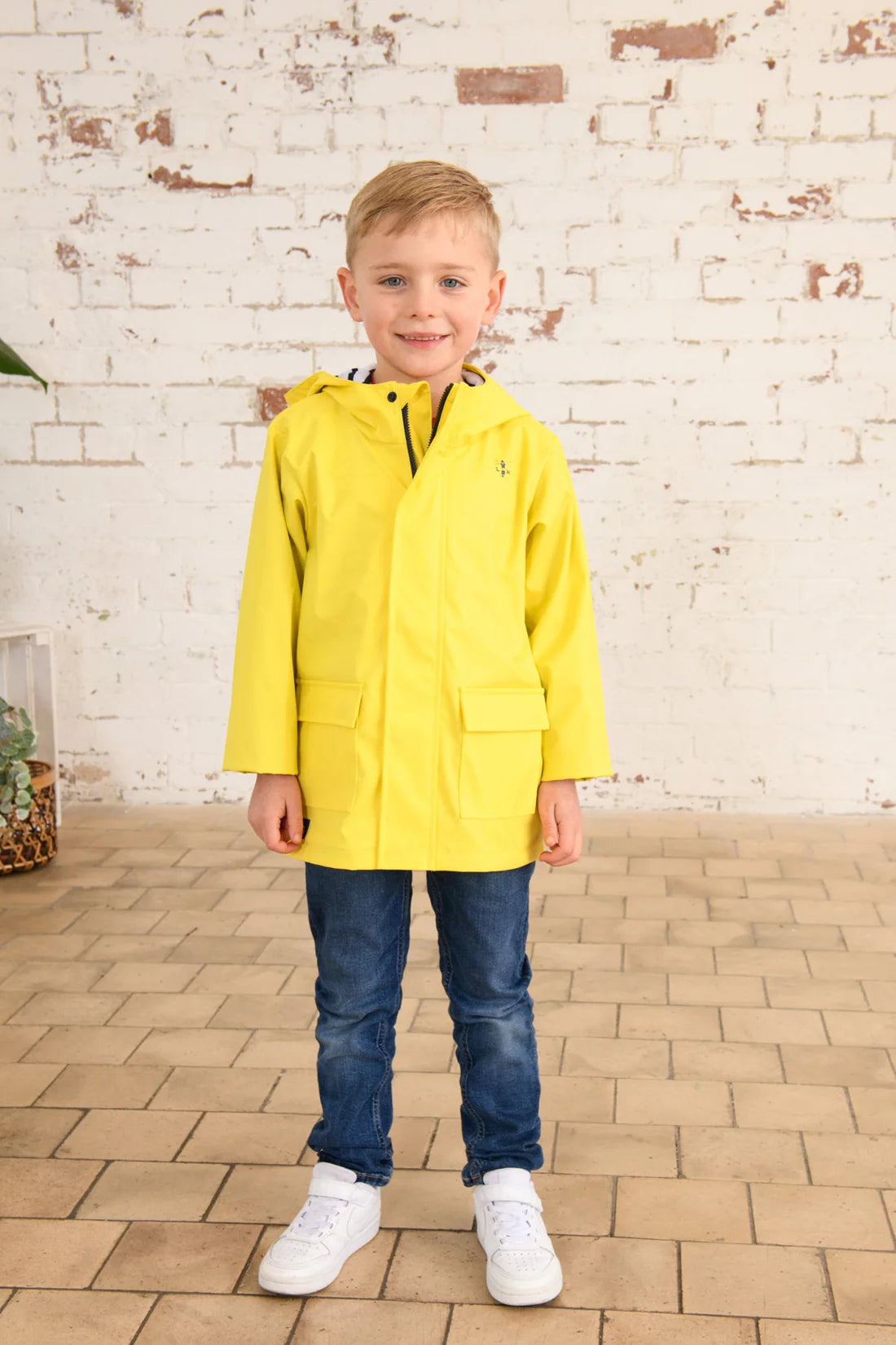 Front view of a kid wearing a yellow Max raincoat by Lighthouse.