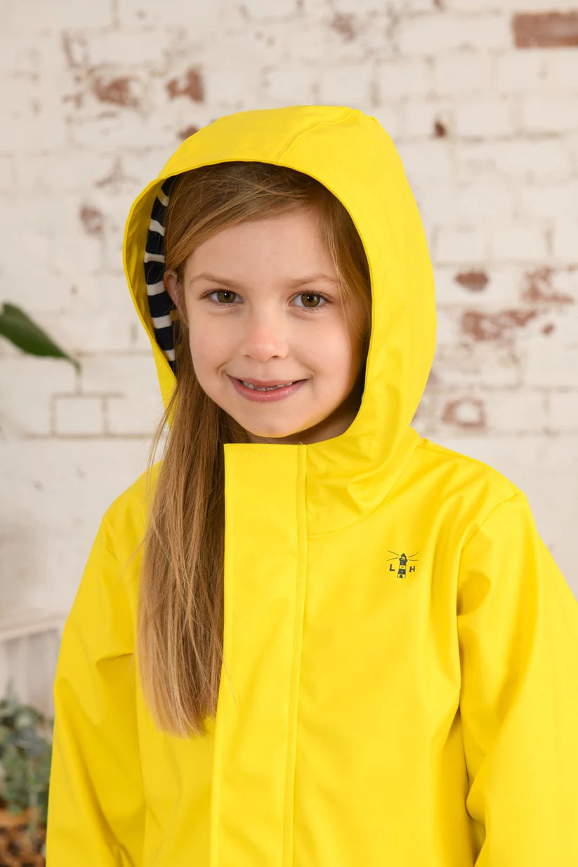 Girl wearing a yellow Max raincoat from Lighthouse with the hood up.