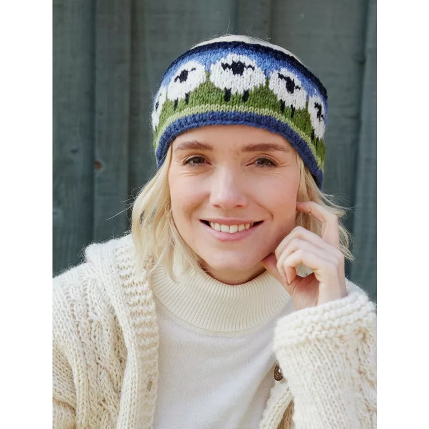 Woman wearing a knitted Pachamama headband with sheep pattern against a grey background