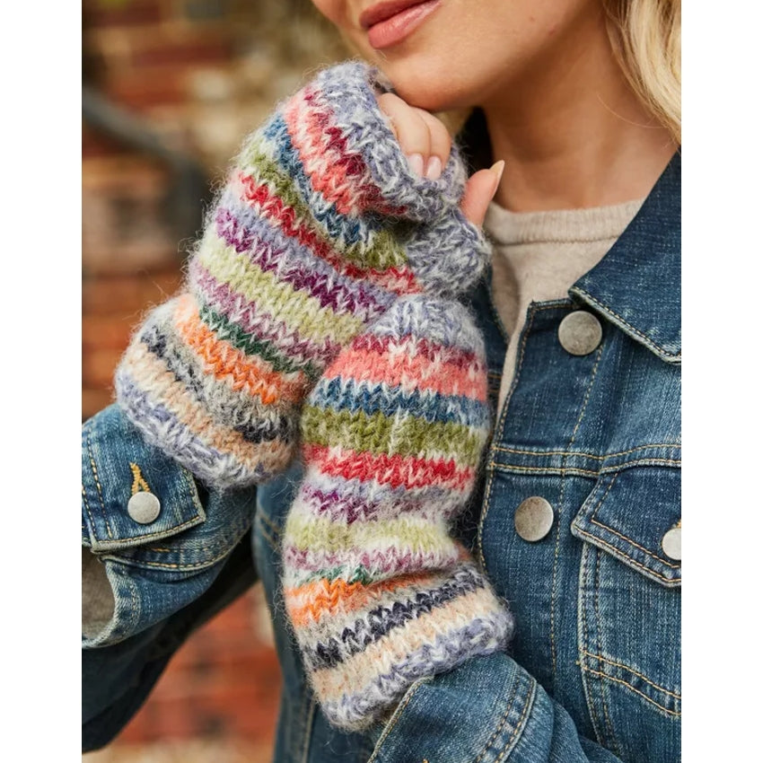 Woman wearing colourful striped Pachamama Coroico handwarmers with a denim jacket.