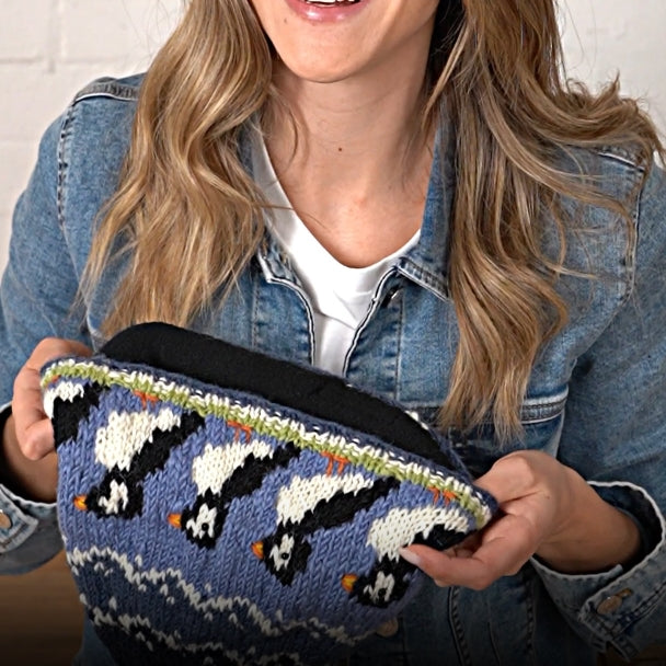 Woman holding a blue Pachamama hat with puffin design and fleece lining