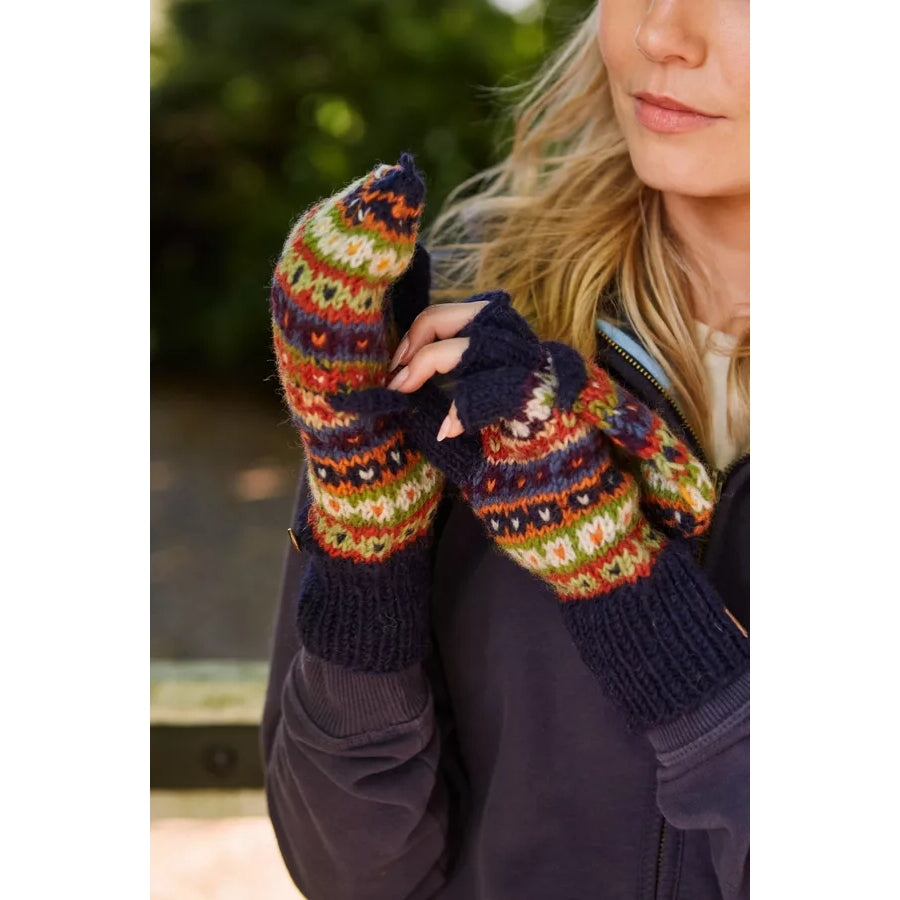 Woman wearing a pair of Pachamama Colorado fingerless glove mittens in a multicolour Fair Isle pattern outdoors.