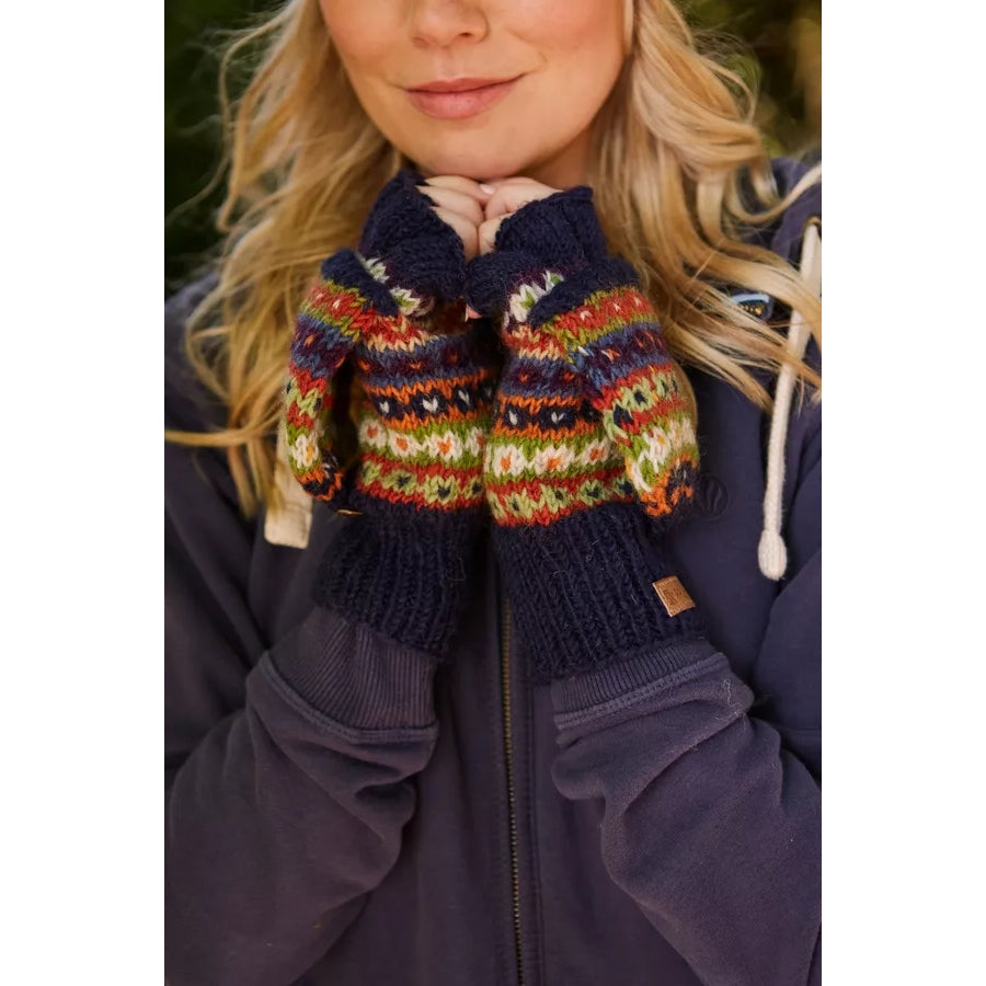 Woman wearing colourful knitted Pachamama fingerless glove mittens with a dark blue jacket.