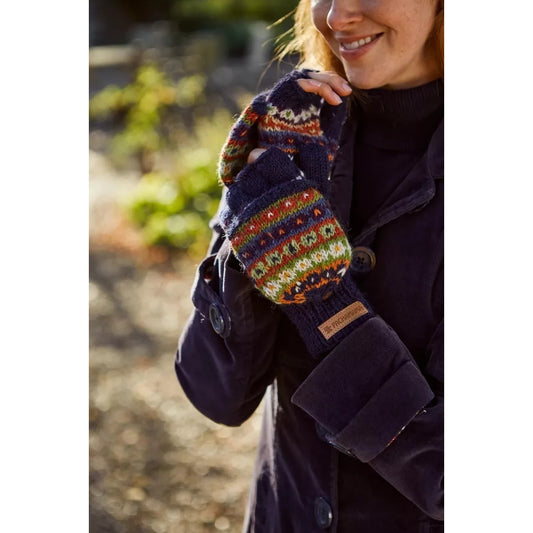 Woman wearing a dark coat and colourful Pachamama knitted fingerless glove mittens outdoors