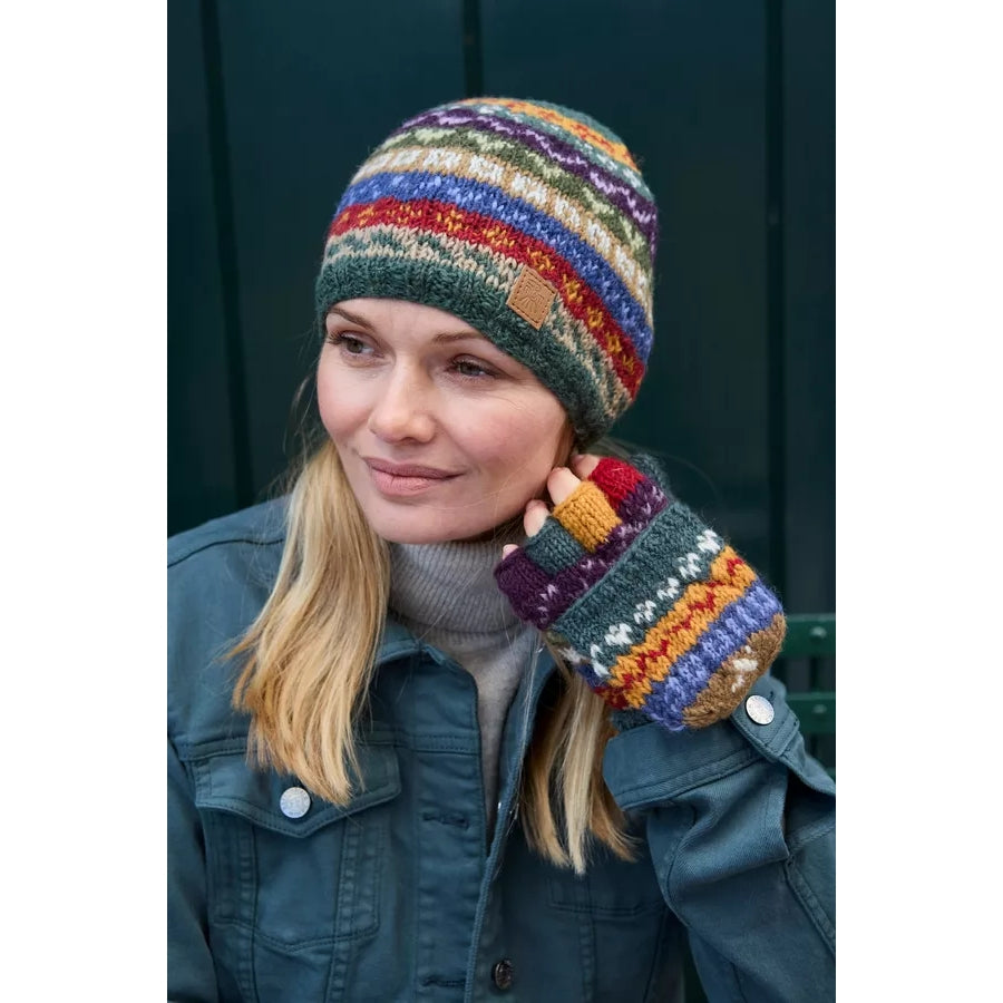 Person wearing colourful knitted Pachamama fingerless gloves in a multicolour Fair Isle pattern outdoors.