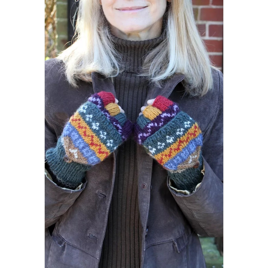 Woman wearing a pair of Pachamama multicolour knitted Elvedon fingerless glove mittens with a Fair Isle pattern stood outside