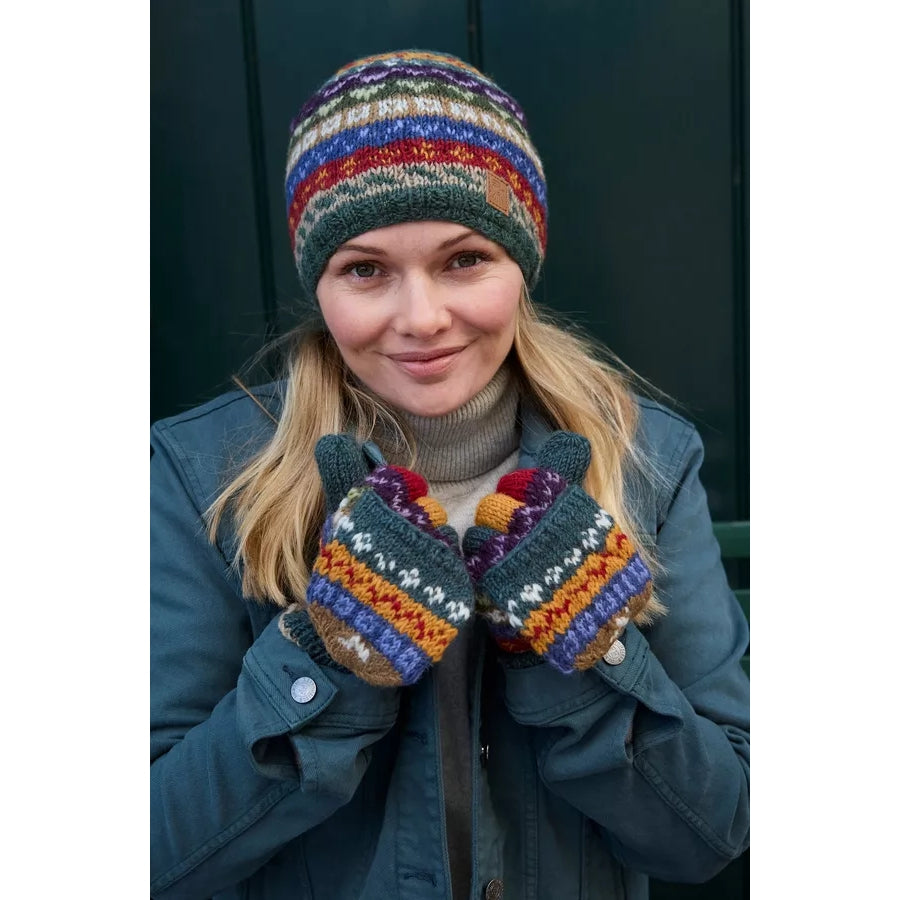 Person wearing colourful striped Pachamama fingerless gloves against a dark background