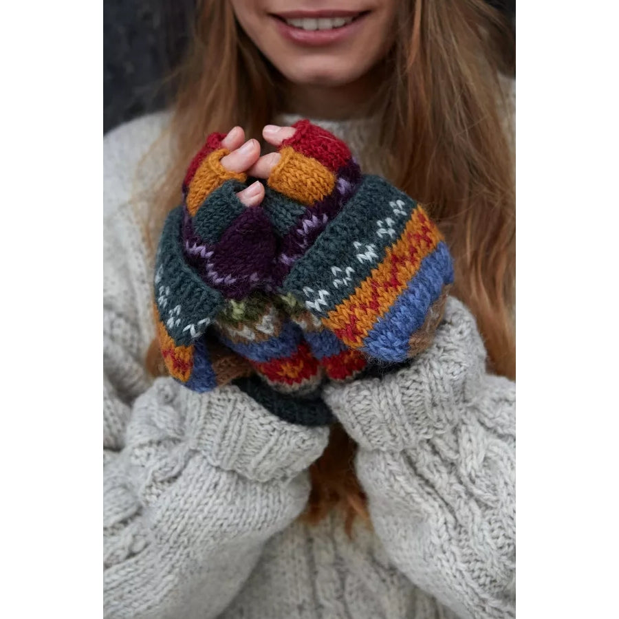 Woman wearing Pachamama Elveden colourful knitted fingerless gloves with a Fair Isle pattern, holding them together.