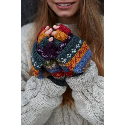 Woman wearing Pachamama Elveden colourful knitted fingerless gloves with a Fair Isle pattern, holding them together.