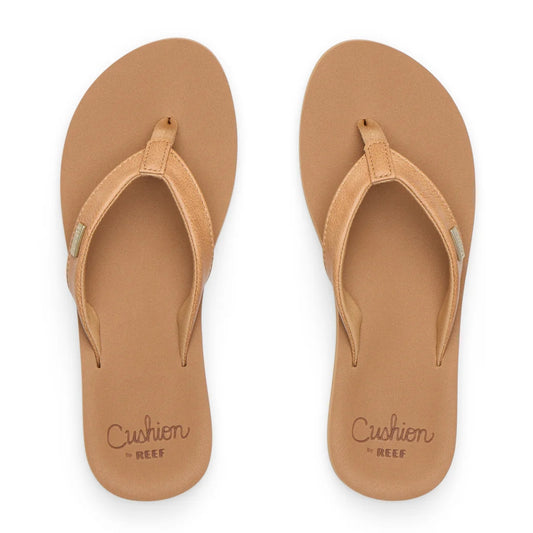 Top view of womens Reef Baja Sands flip flops in Almond brown with gold logo label on the strap and cushion sole branding.