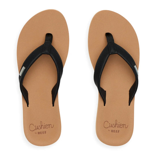 Top view of womens Reef Baja Sands flip flops in tan with black straps and cushion sole branding.