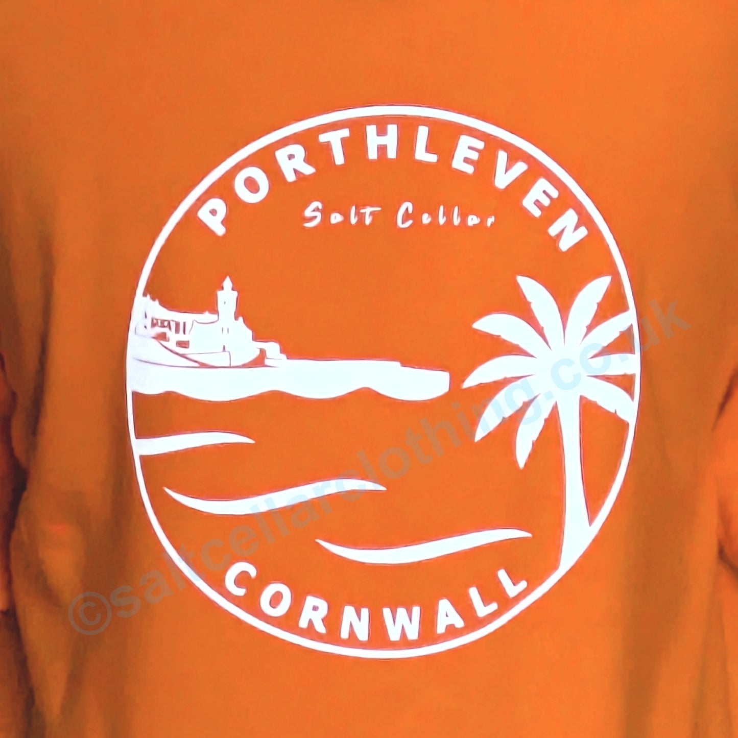 Orange t-shirt with white graphic design of Porthleven, Cornwall featuring harbour, clocktower and palm tree.
