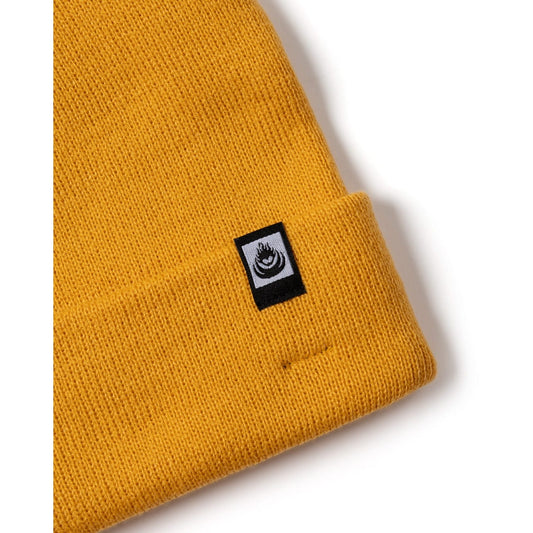 Yellow Saltrock knit beanie with a black logo label on a white background