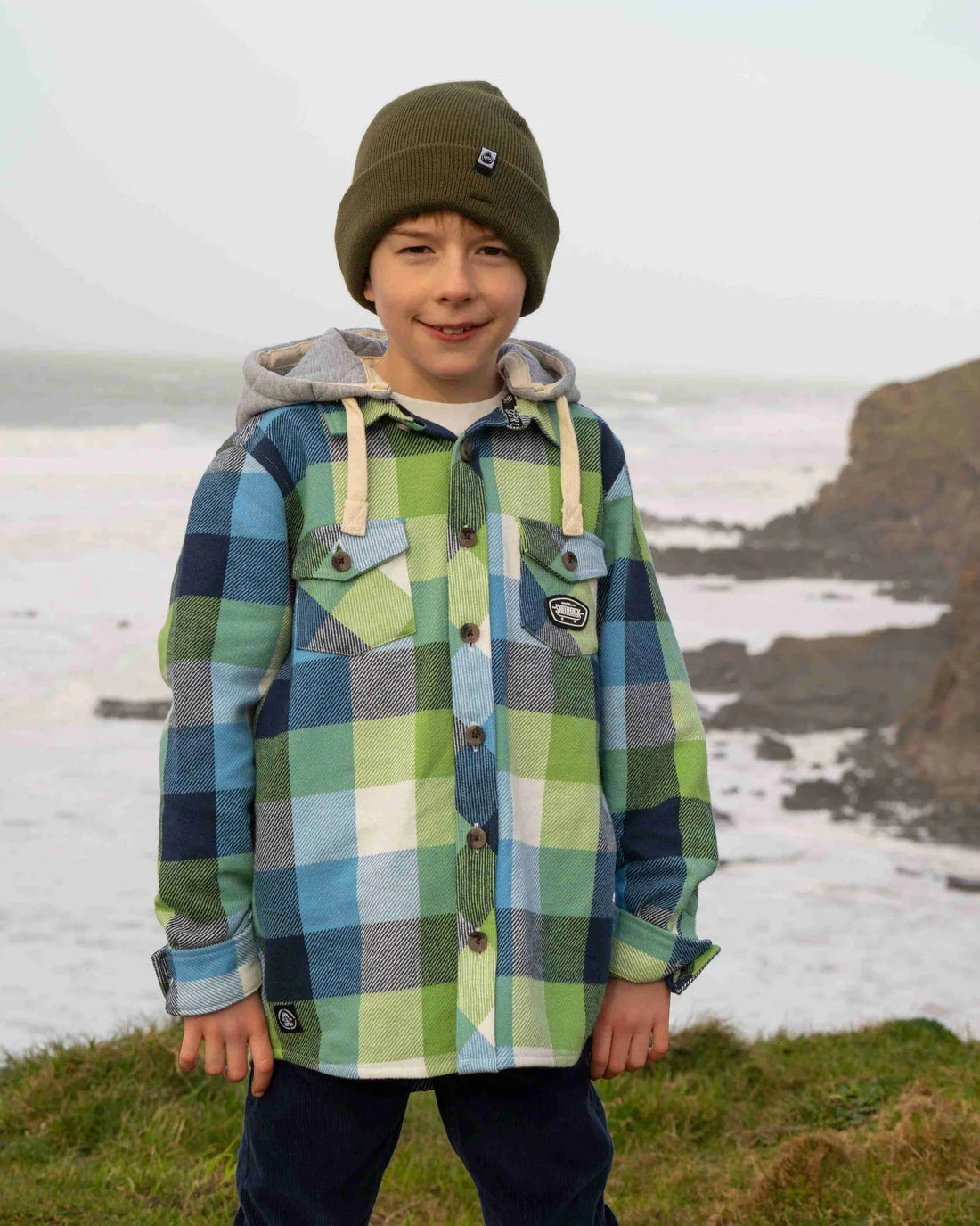 Saltrock kids check shirt in blue and green worn by a boy with a beanie by the seaside